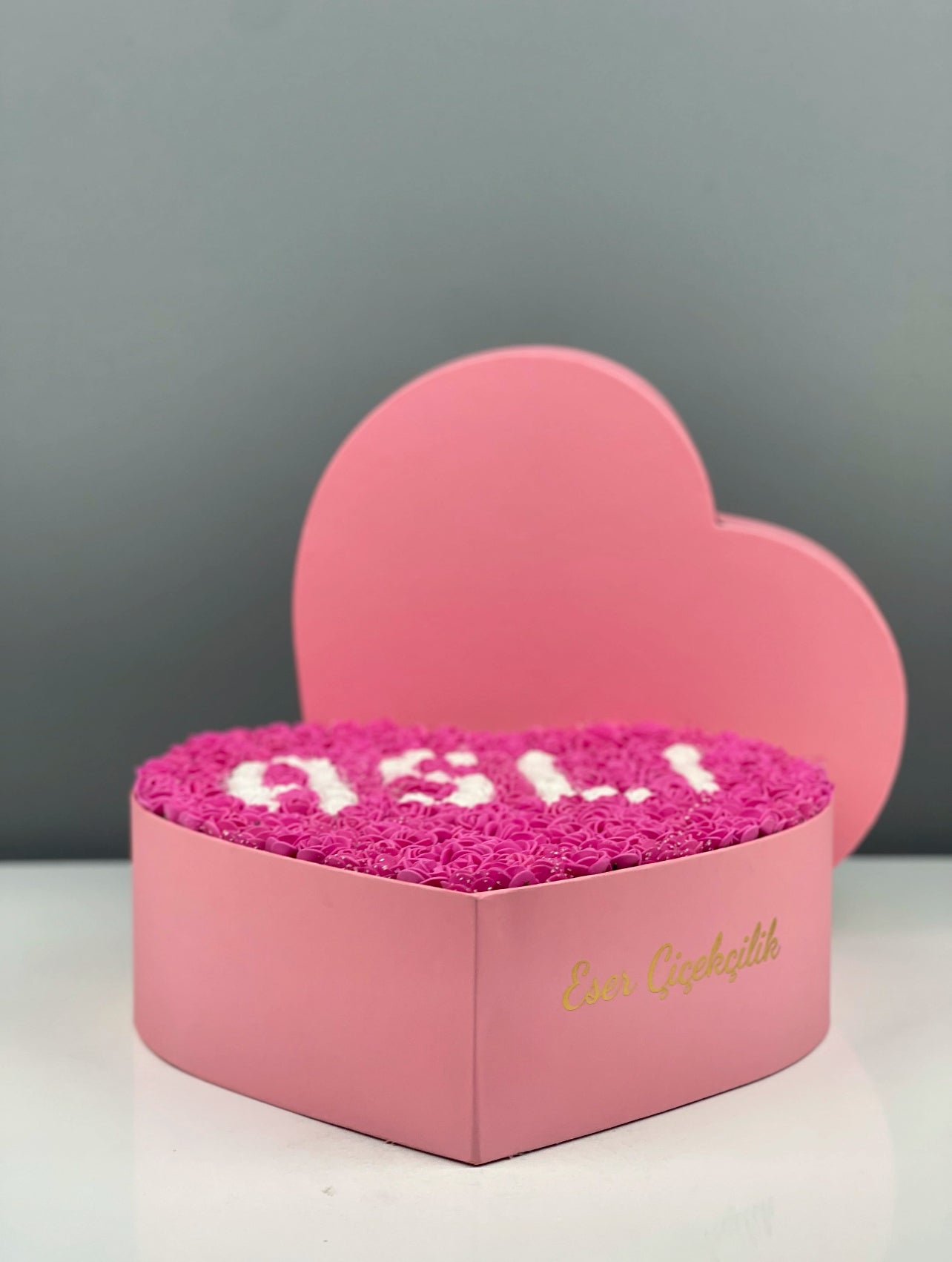 Fuşya lateks güller arasındaki beyaz güllerle yapılmış isim tasarımının yakın çekim görüntüsü