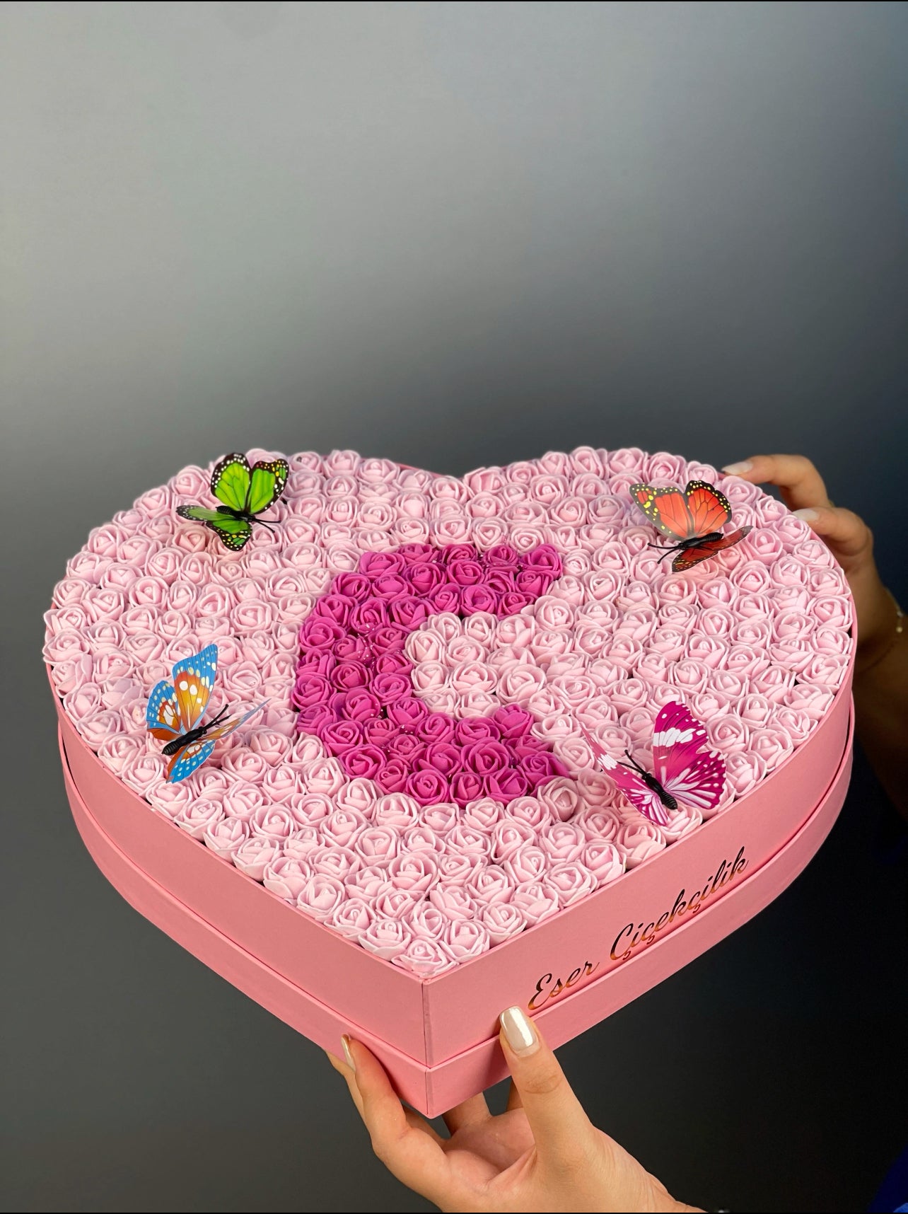 Üstten bakışta 37 cm pembe kalp kutuda pembe ve fuşya güllerle yapılmış harf tasarım düzeni