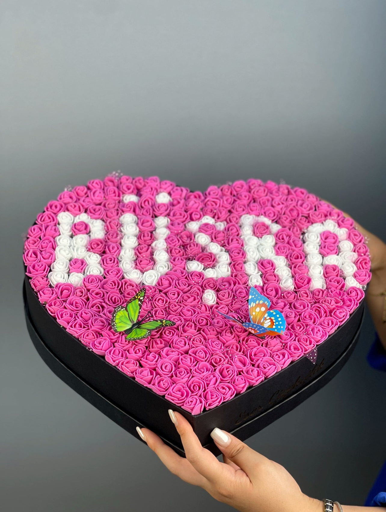Üstten bakışta 37 cm siyah kalp kutuda fuşya ve beyaz güllerle yapılmış isim tasarım düzeni