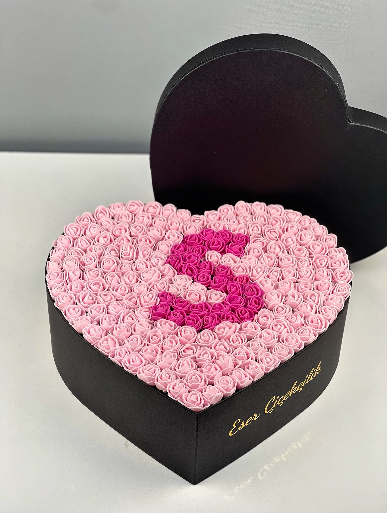 Kalp kutu içindeki pembe güller üzerine yapılan fuşya harf tasarımının yakın çekim detayı