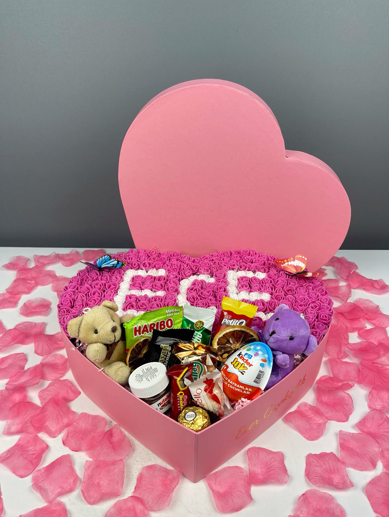 Yakın çekim: Fuşya güllerin üzerine beyaz güllerle yazılmış isim detayının net görüntüsü.