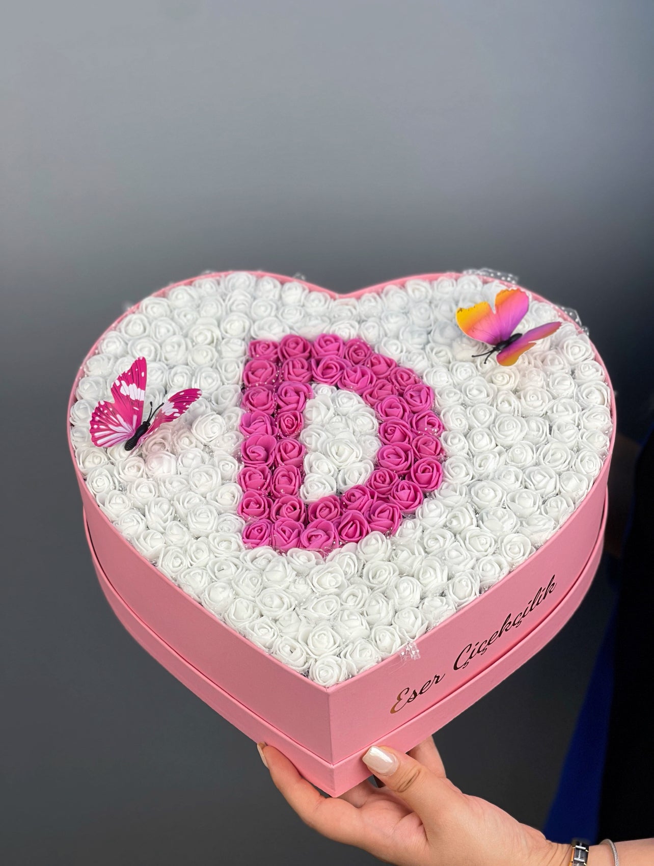 Üstten bakışta 31 cm pembe kalp kutuda beyaz ve fuşya güllerle oluşturulmuş harf tasarım düzeni
