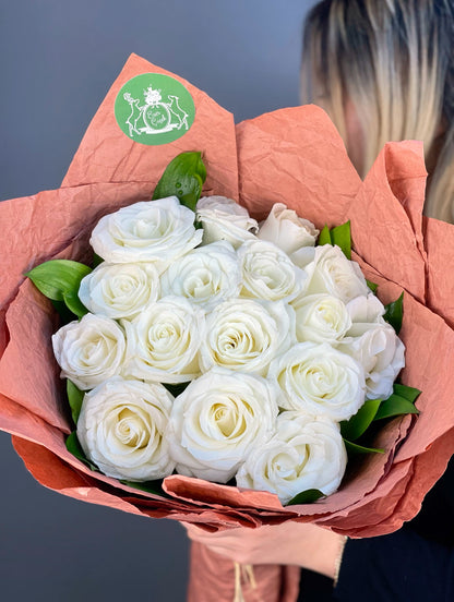 Beyaz güllerin asaleti ve ruskus yapraklarının doğal dokunuşuyla tamamlanan romantik buket.