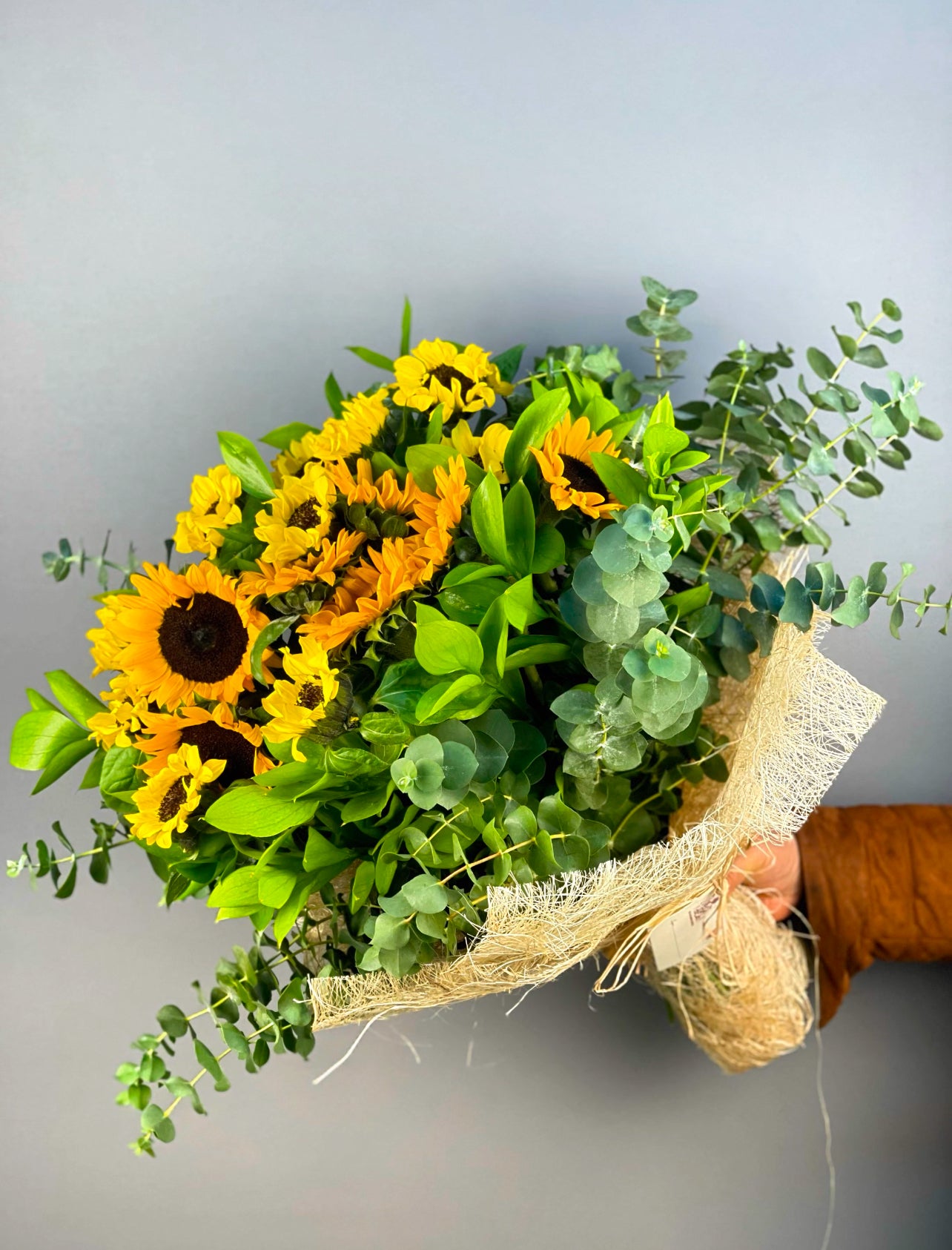 Sunshine Joy Ayçiçeği Buketi, 17 adet canlı sarı ayçiçeği, okaliptus ve ruskus ile hazırlanmış enerjik bir aranjmandır. Abaka ile zarifçe sarılmış olan bu büyük buket, mutluluk ve pozitif enerji gönderiyor. İstanbul içi hızlı teslimat seçeneğiyle sevdiklerinize taze çiçeklerle sürpriz yapın.