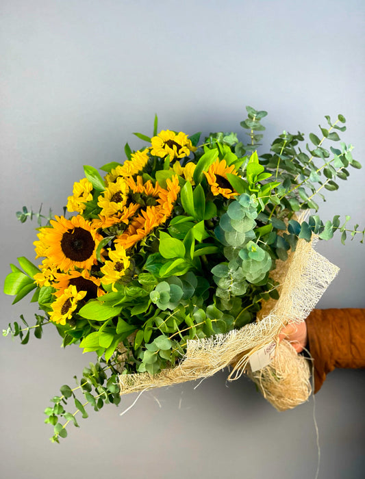 Sunshine Joy Ayçiçeği Buketi, 17 adet canlı sarı ayçiçeği, okaliptus ve ruskus ile hazırlanmış enerjik bir aranjmandır. Abaka ile zarifçe sarılmış olan bu büyük buket, mutluluk ve pozitif enerji gönderiyor. İstanbul içi hızlı teslimat seçeneğiyle sevdiklerinize taze çiçeklerle sürpriz yapın.