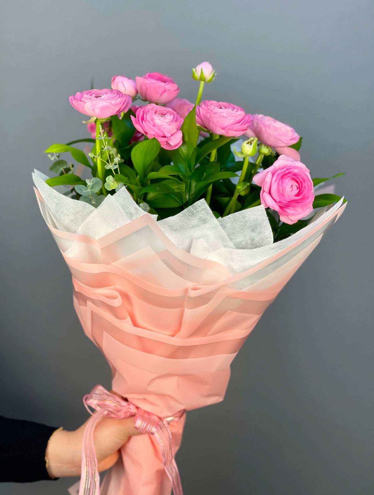 Rosy Elegance El Buketi: 10 adet taze pembe erengül ve ruskus ile hazırlanmış, şık pembe ambalajlı zarif bir el buketi.