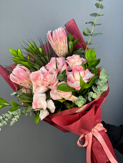 Pembe protea ve ithal güllerin şık düzenlemesini yakından gösteren detay görüntüsü.