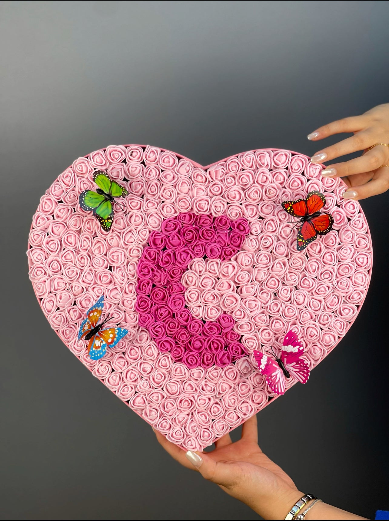 Grande boy pembe kutunun yandan görünümünde pembe güller ve fuşya güllerle oluşturulmuş harf tasarımı detayı
